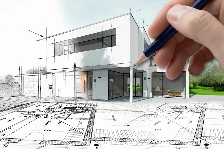 An architect sketching a modern house rendering over blueprints, IT services for architecture firms