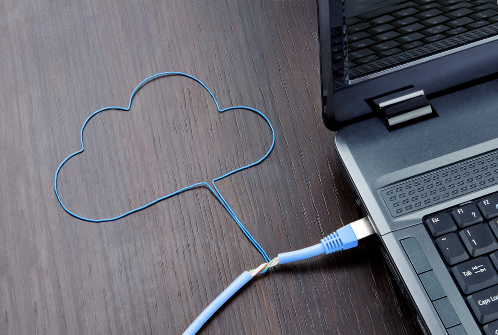A network cable shaped like a cloud plugged into a laptop, representing managed cloud connectivity