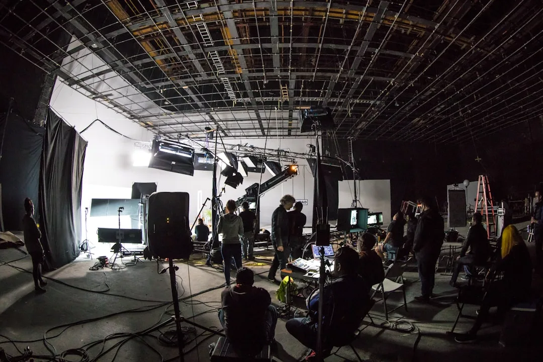 A film crew on a soundstage with lighting rigs, cameras, and monitors during a production shoot