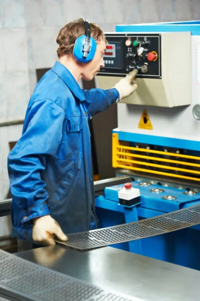 A manufacturing operator running a metal press machine on the shop floor