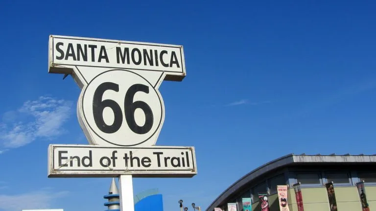The Santa Monica Route 66 'End of the Trail' sign against a blue sky at the Santa Monica Pier